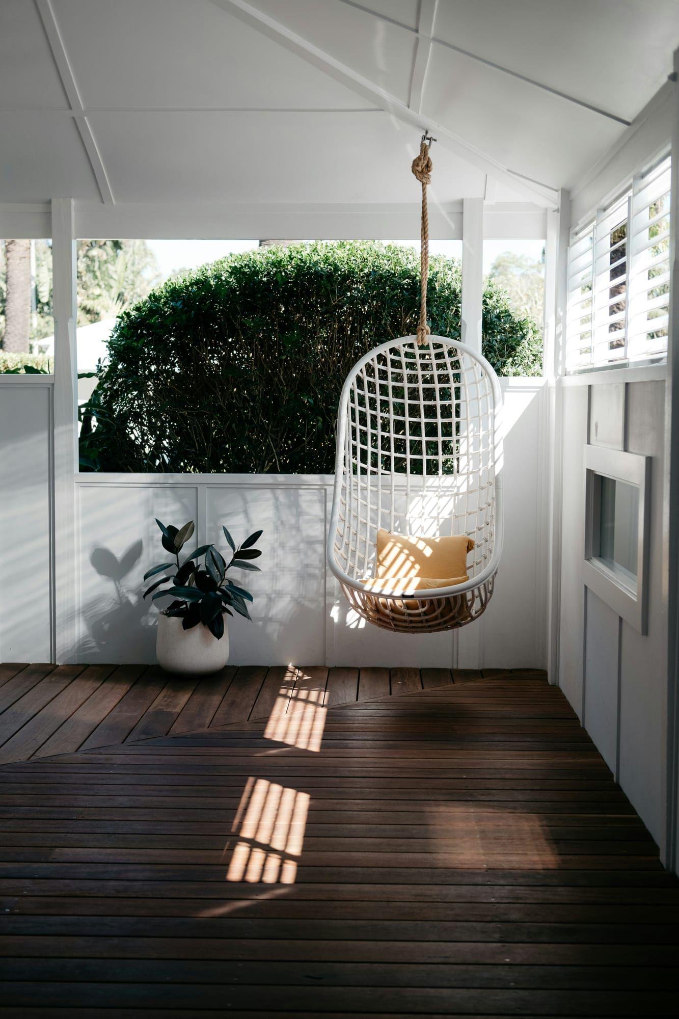 Covered porch with dark stained wood decking and a hanging swing chair
