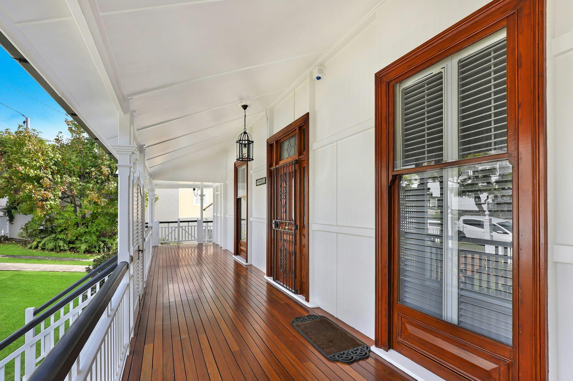 Wraparound porch with rich stained wood decking and white railings