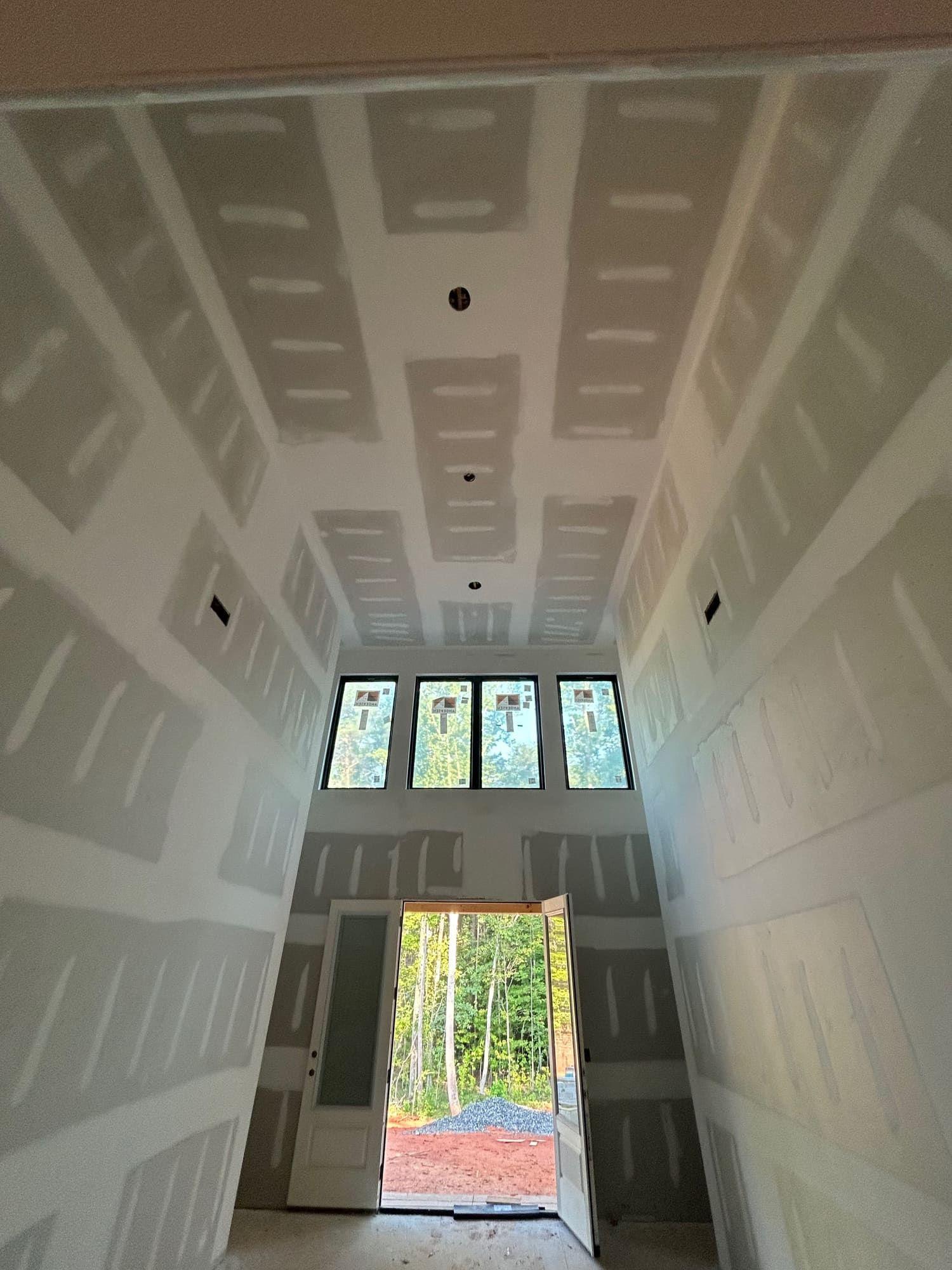 Tall drywall entryway with finished seams, view to front door