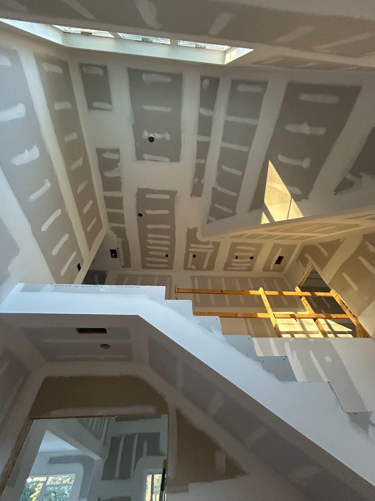 Drywall finishing on staircase landing with skylight