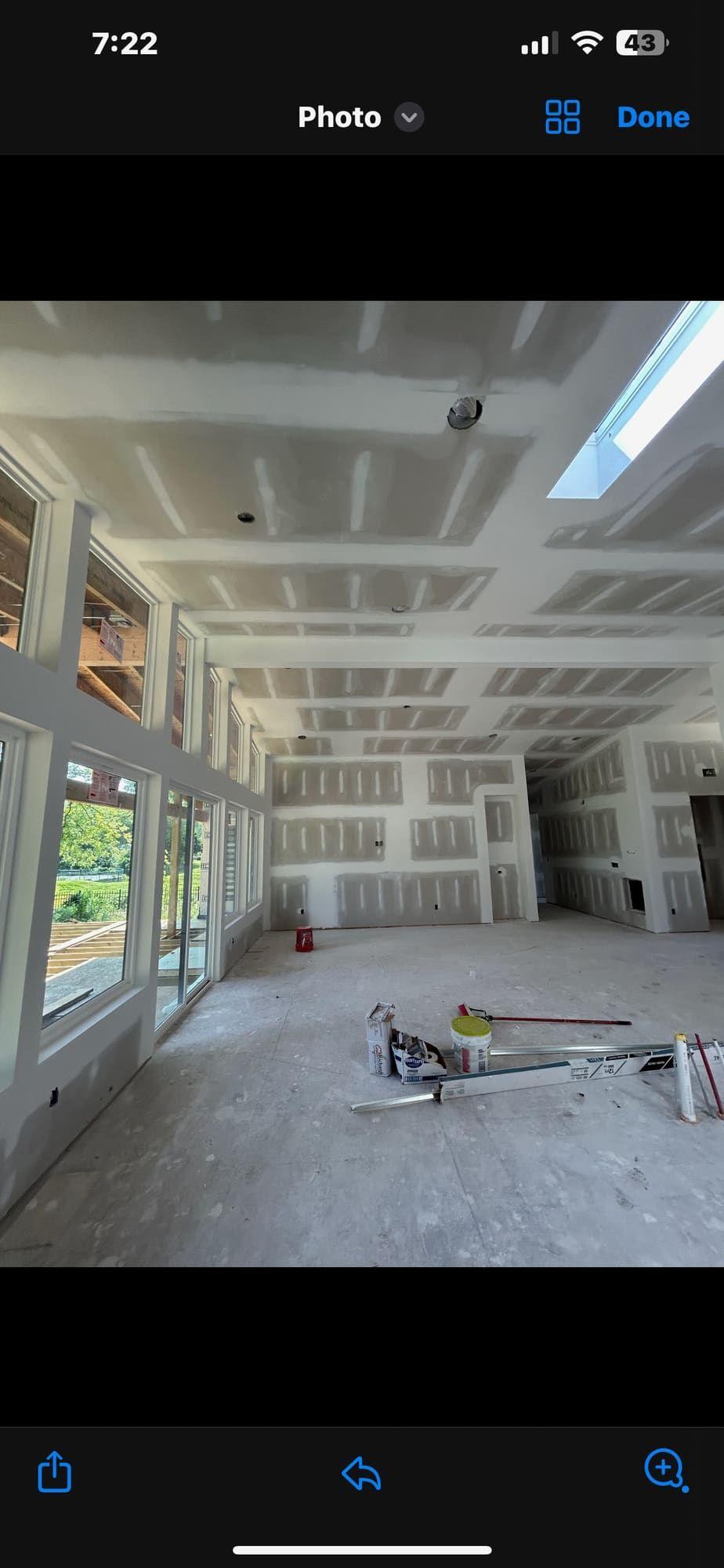 Drywall finishing in great room with skylights and large windows
