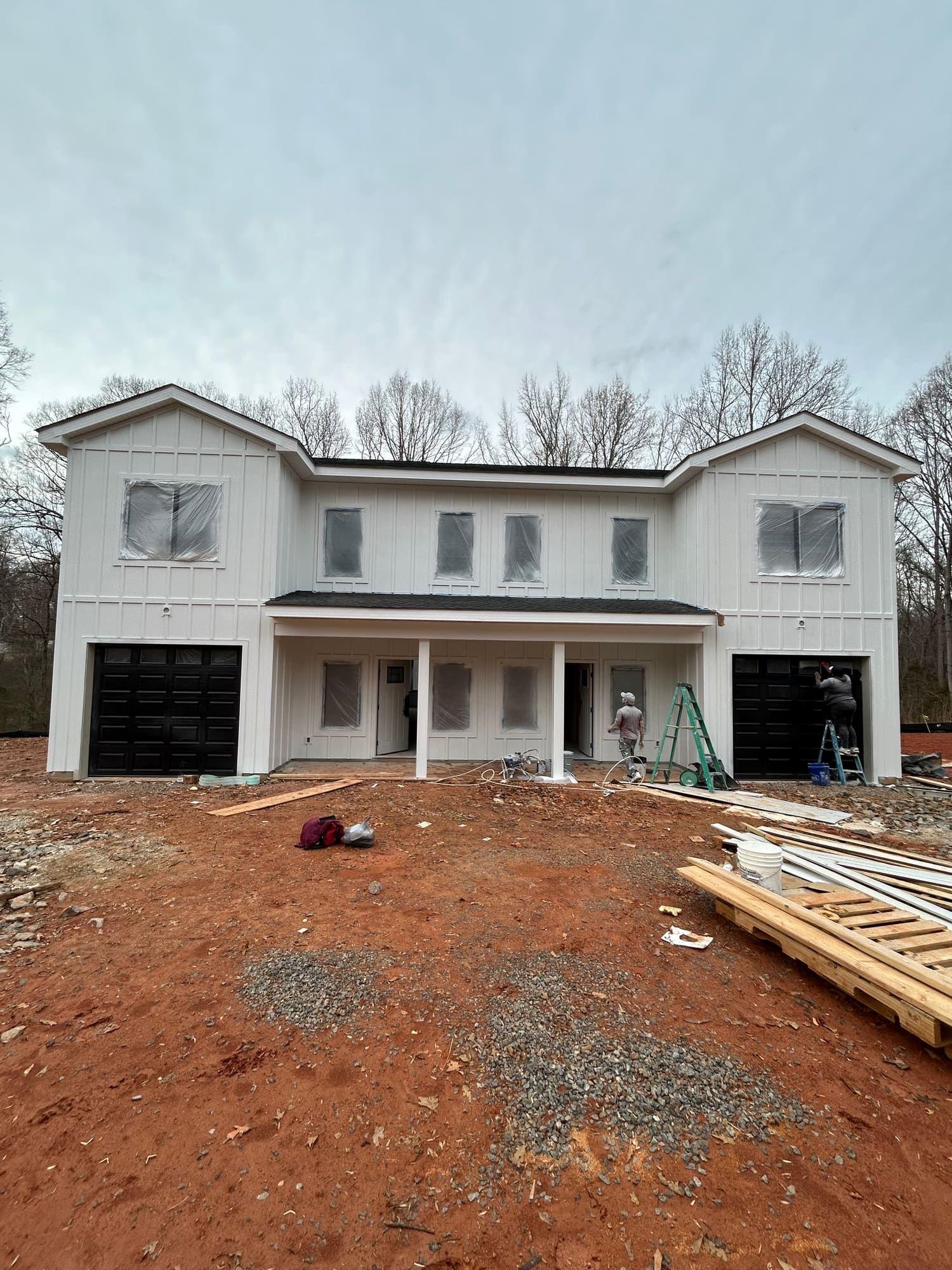 Two-story home exterior painted white with black accents, front view