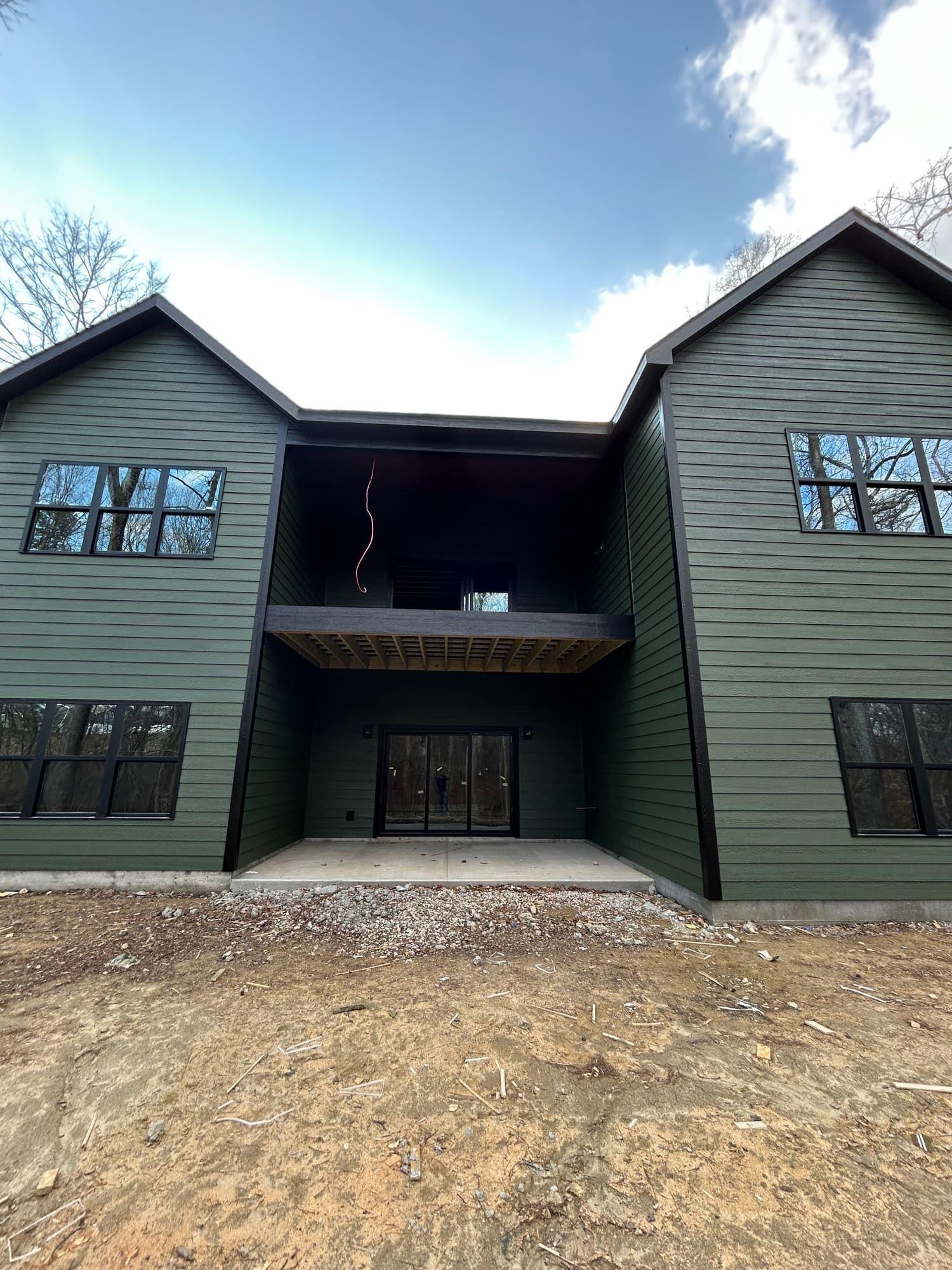 Two-story home exterior painted dark green with black trim, rear elevation