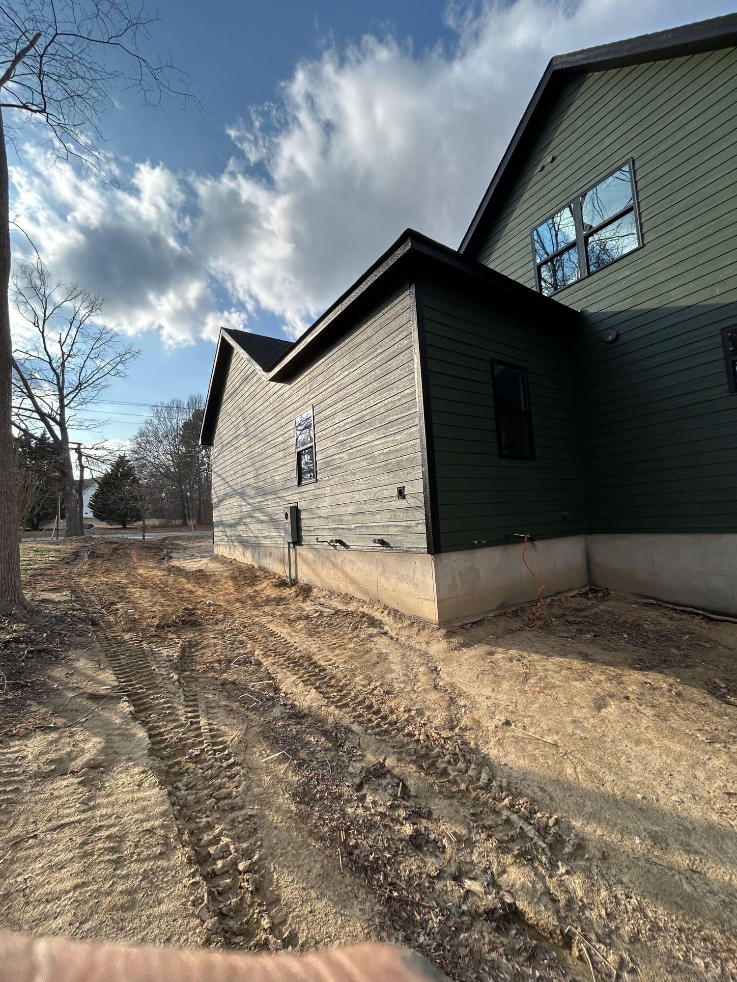 Green exterior paint job in progress, side of home with foundation wrap