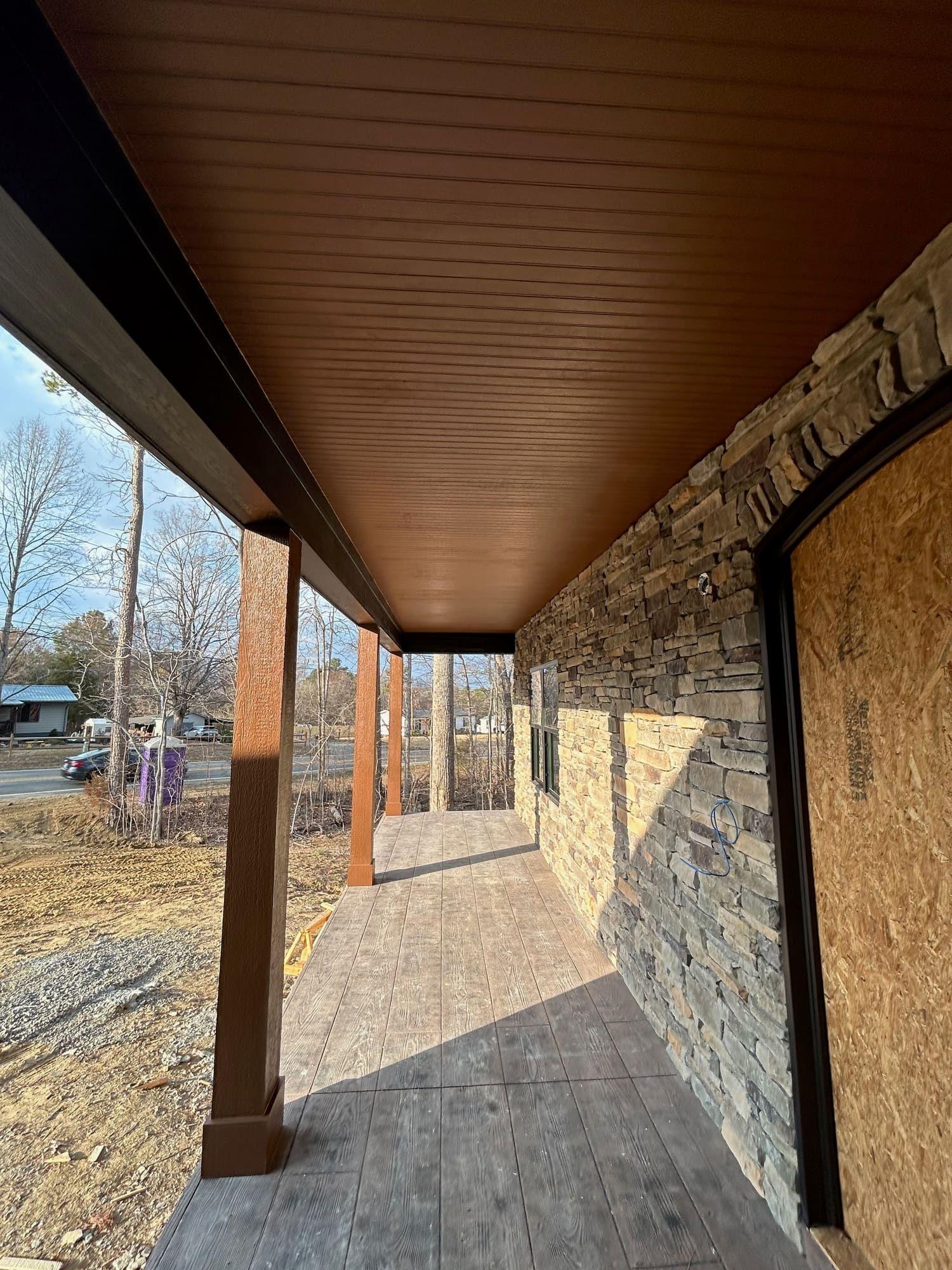 Stained wood porch ceiling and stone accent wall, covered walkway
