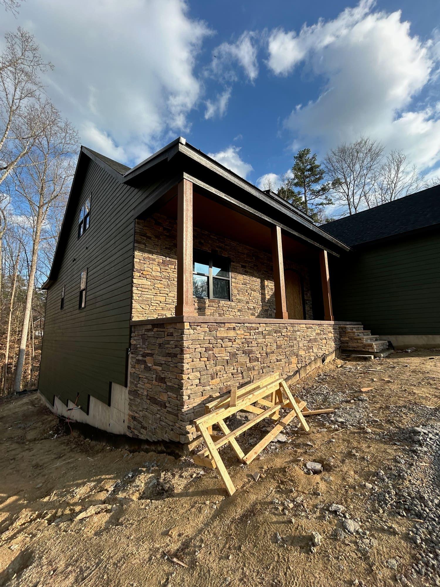 Dark green siding with stone base, covered entry porch