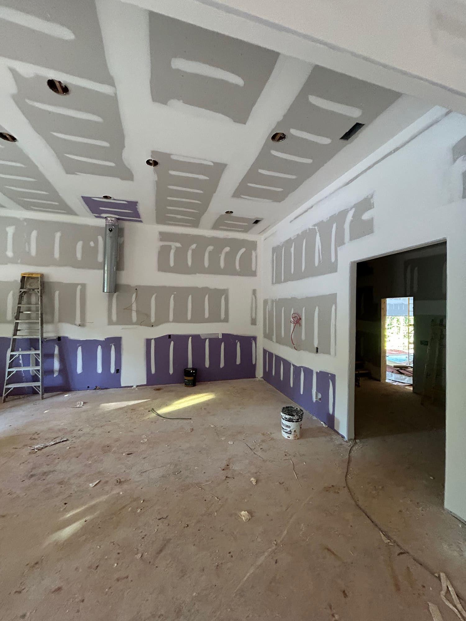 Interior accent wall painted purple alongside primed drywall