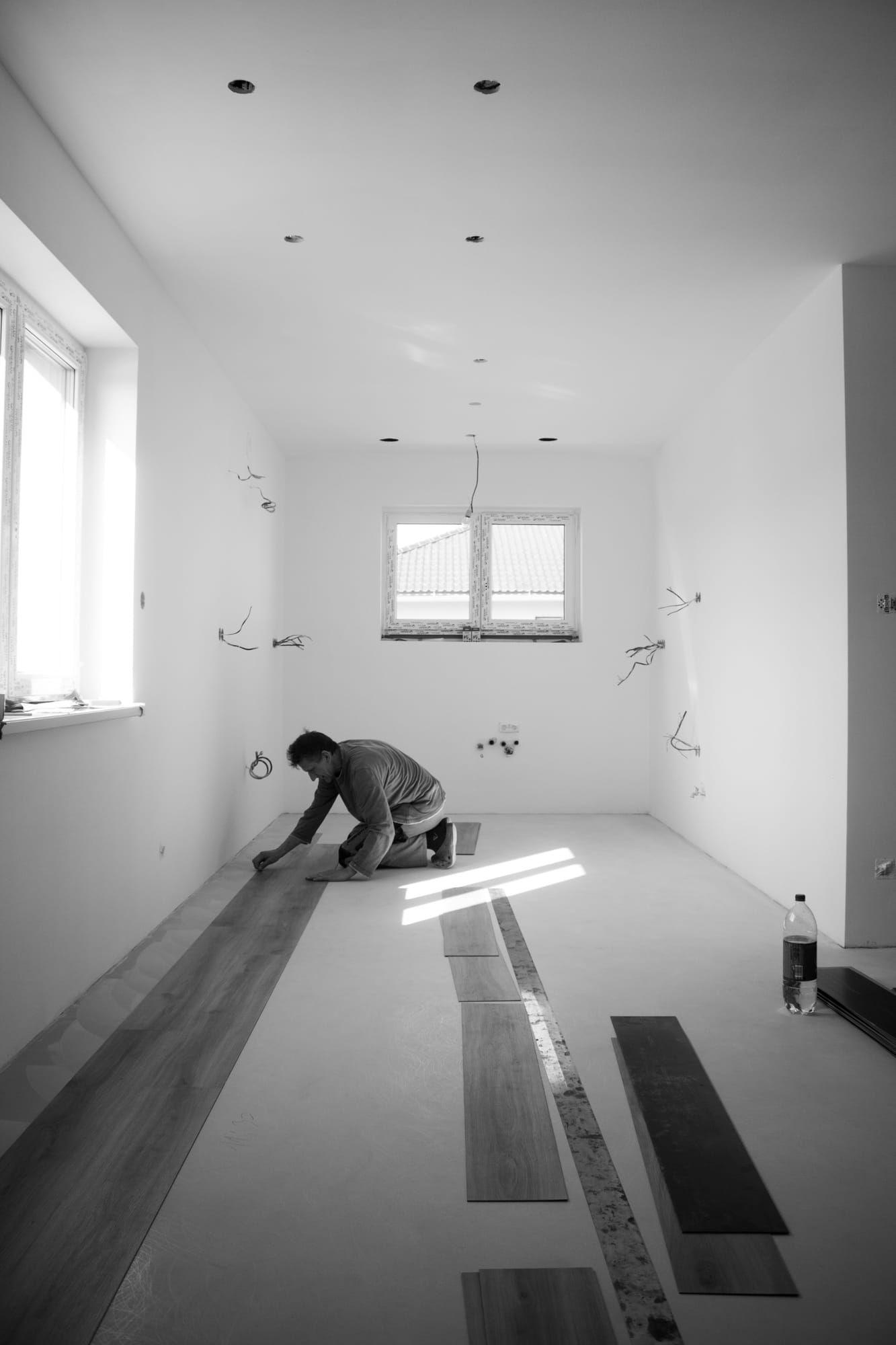 Installer laying vinyl plank flooring in an empty room